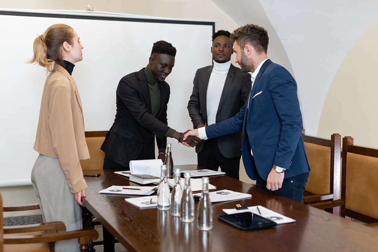 A diverse group of professionals engaged in a business meeting, sealing a deal with a handshake.